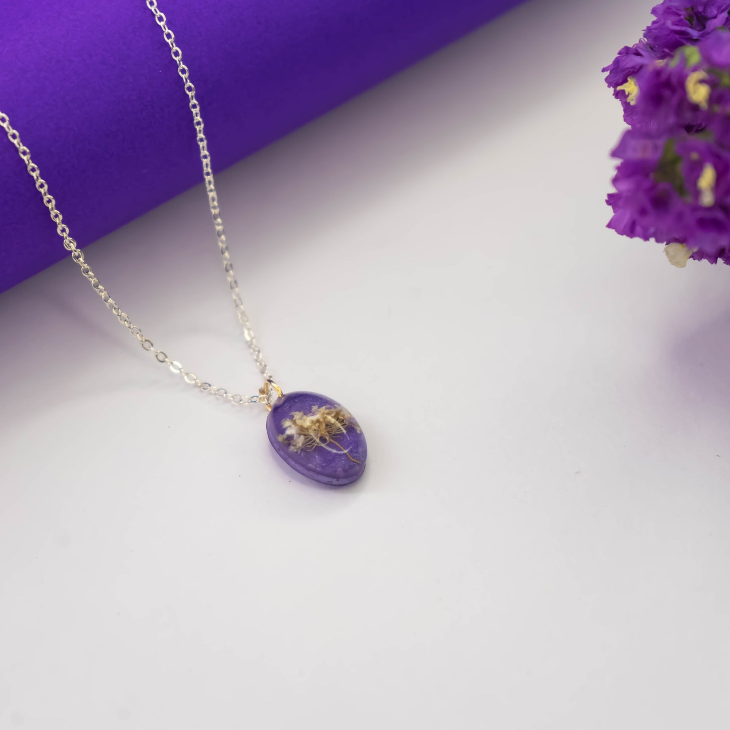 A collection of handmade resin art pendants, showcasing intricate floral designs preserved in clear resin, attached to delicate necklaces.