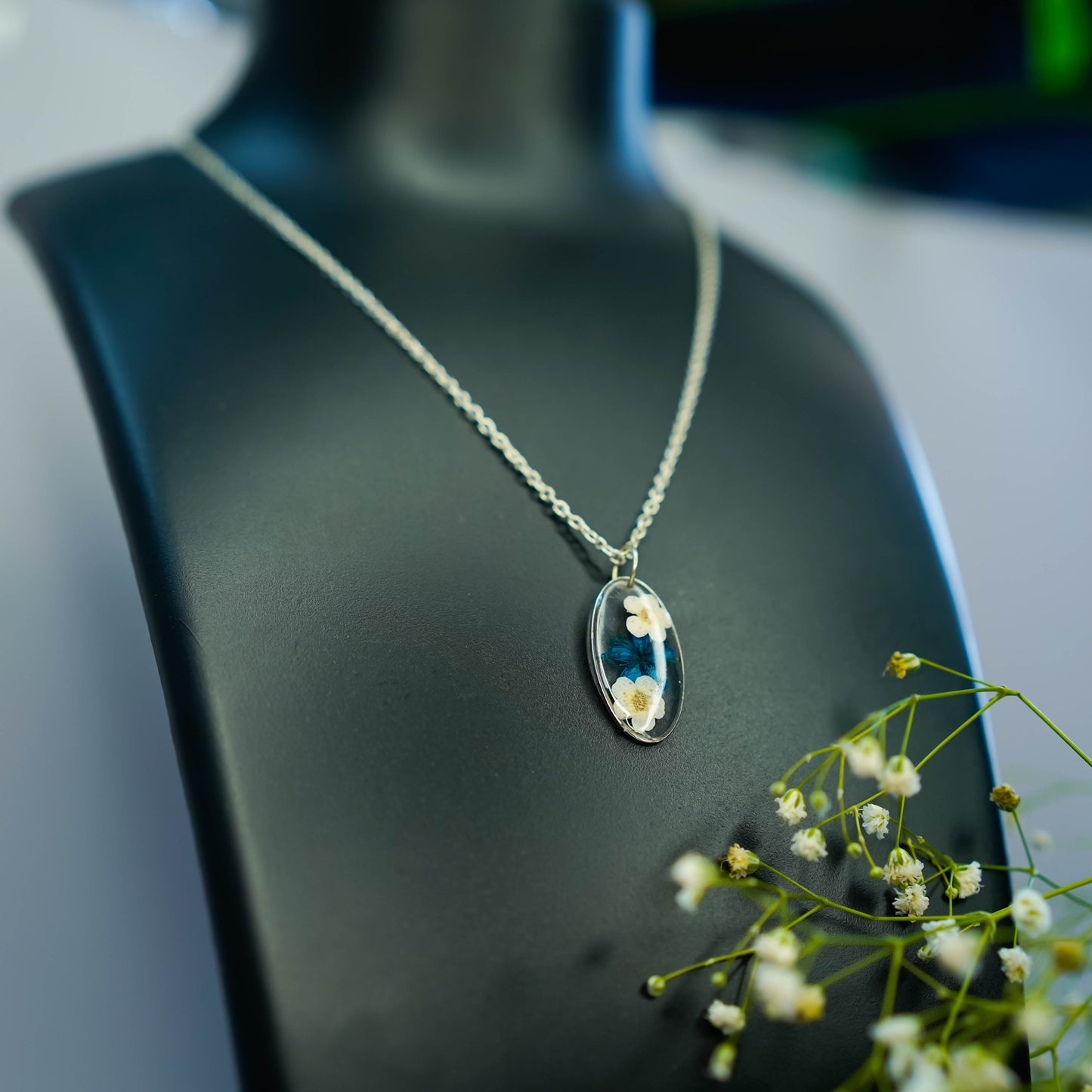 A collection of handmade resin art pendants, showcasing intricate floral designs preserved in clear resin, attached to delicate necklaces.