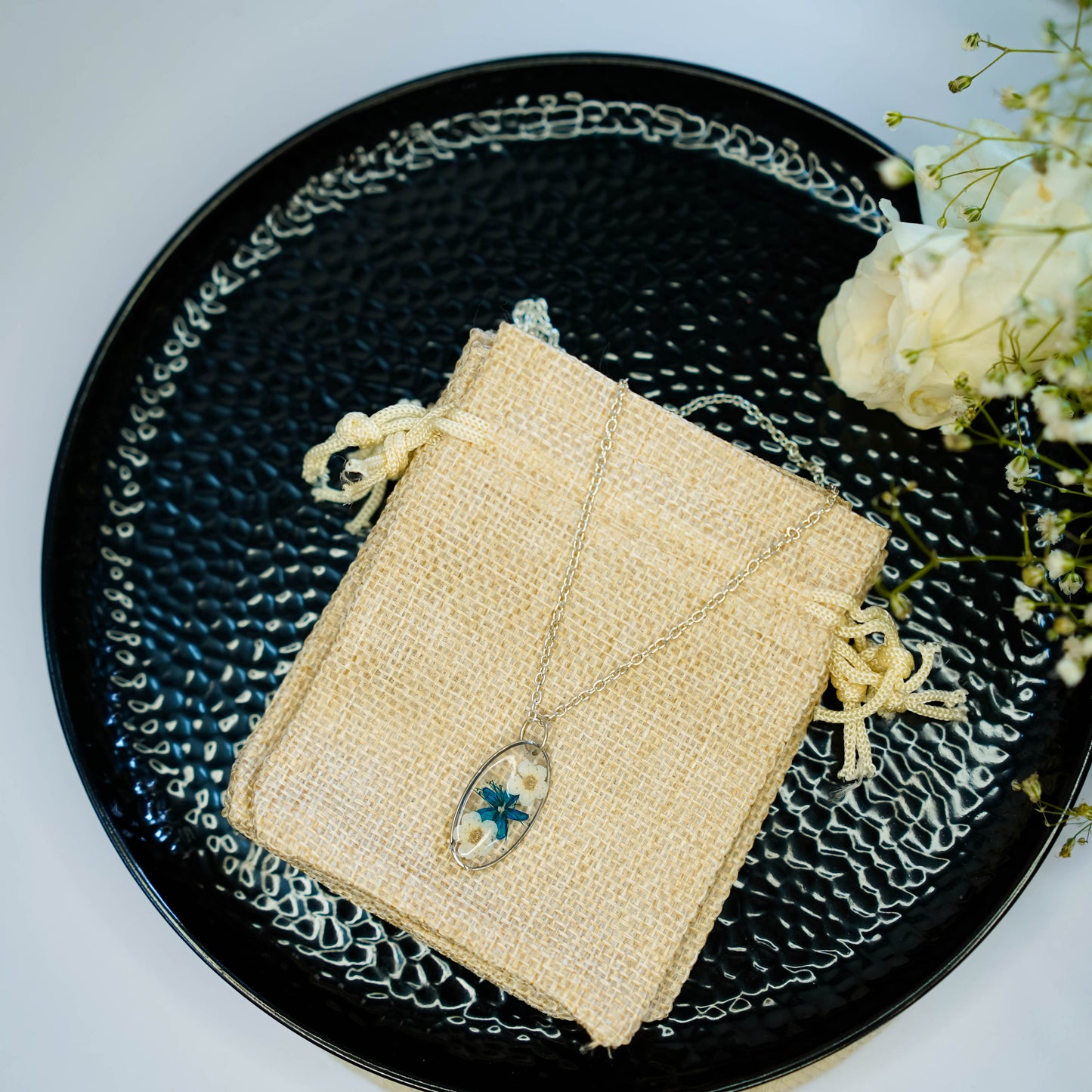 A collection of handmade resin art pendants, showcasing intricate floral designs preserved in clear resin, attached to delicate necklaces.
