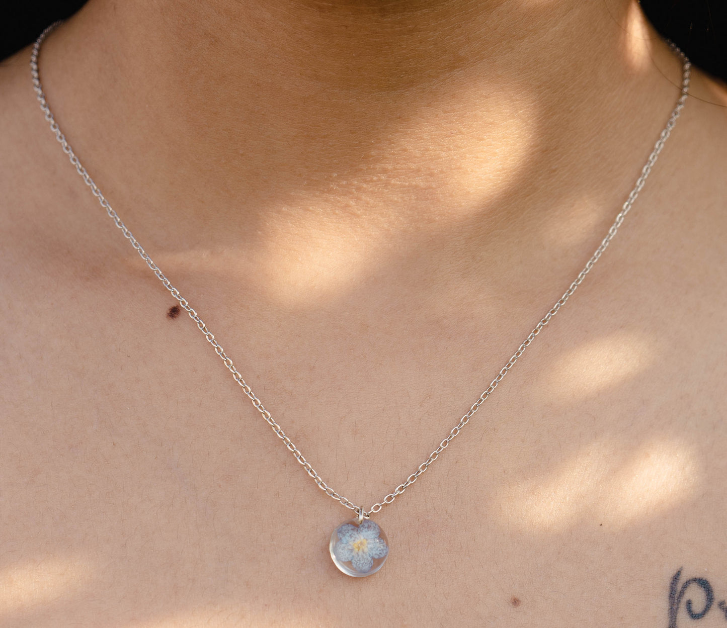 A collection of handmade resin art pendants, showcasing intricate floral designs preserved in clear resin, attached to delicate necklaces.
