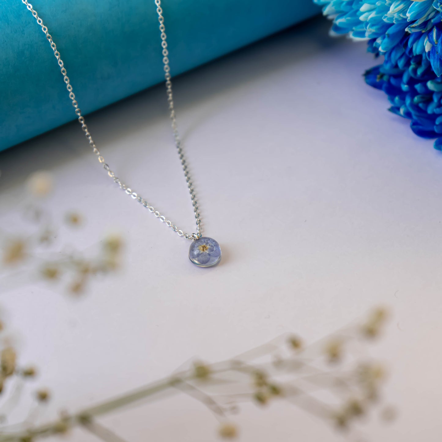A collection of handmade resin art pendants, showcasing intricate floral designs preserved in clear resin, attached to delicate necklaces.