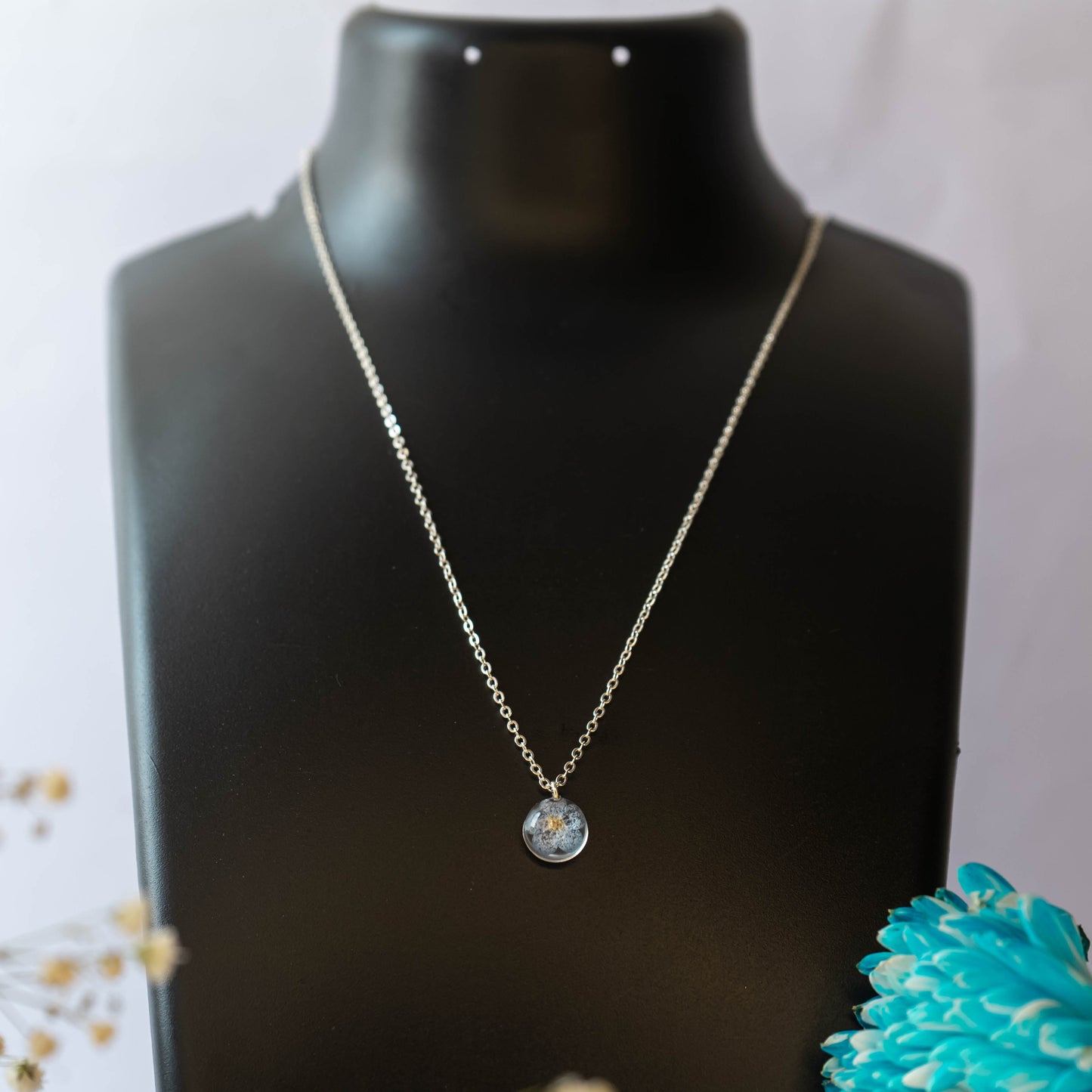 A collection of handmade resin art pendants, showcasing intricate floral designs preserved in clear resin, attached to delicate necklaces.