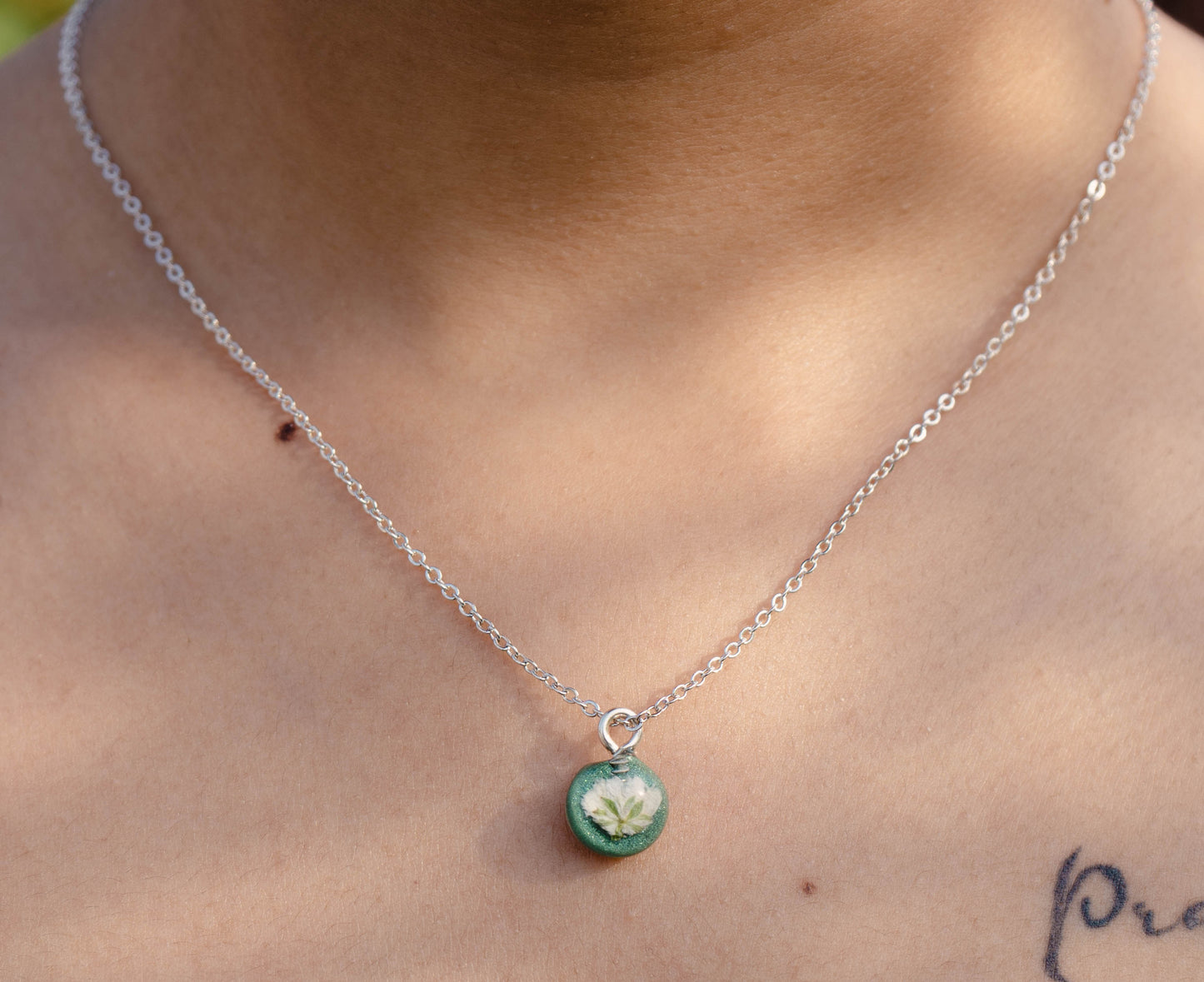 A collection of handmade resin art pendants, showcasing intricate floral designs preserved in clear resin, attached to delicate necklaces.
