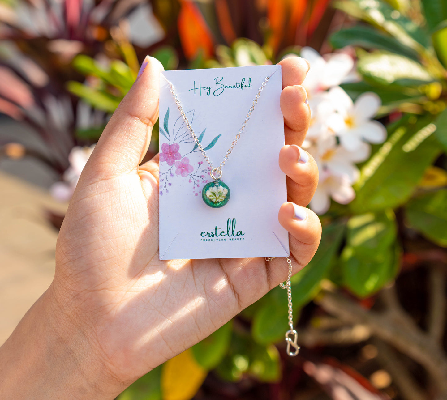 A collection of handmade resin art pendants, showcasing intricate floral designs preserved in clear resin, attached to delicate necklaces.