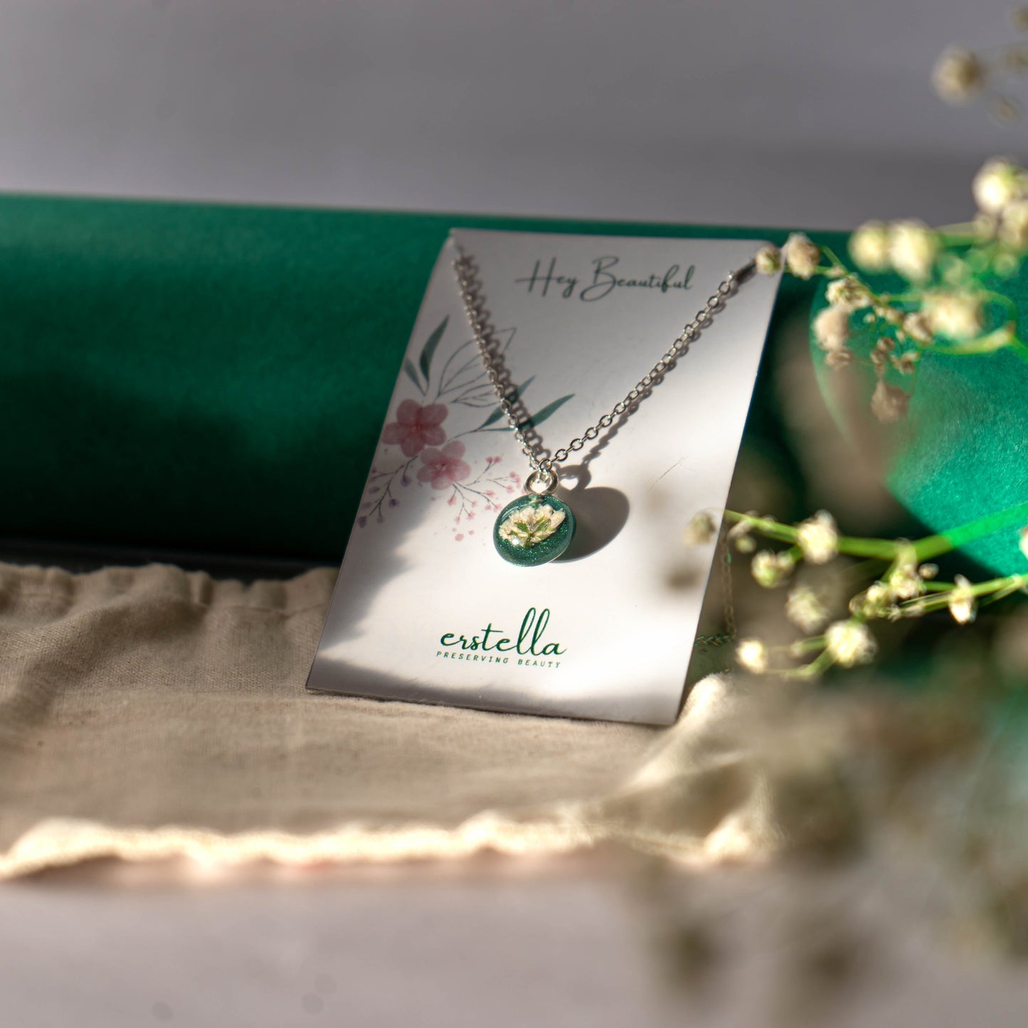 A collection of handmade resin art pendants, showcasing intricate floral designs preserved in clear resin, attached to delicate necklaces.