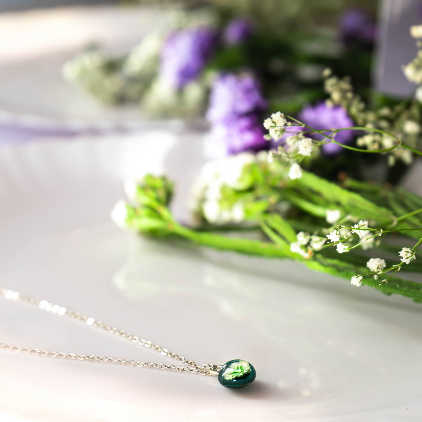 A collection of handmade resin art pendants, showcasing intricate floral designs preserved in clear resin, attached to delicate necklaces.