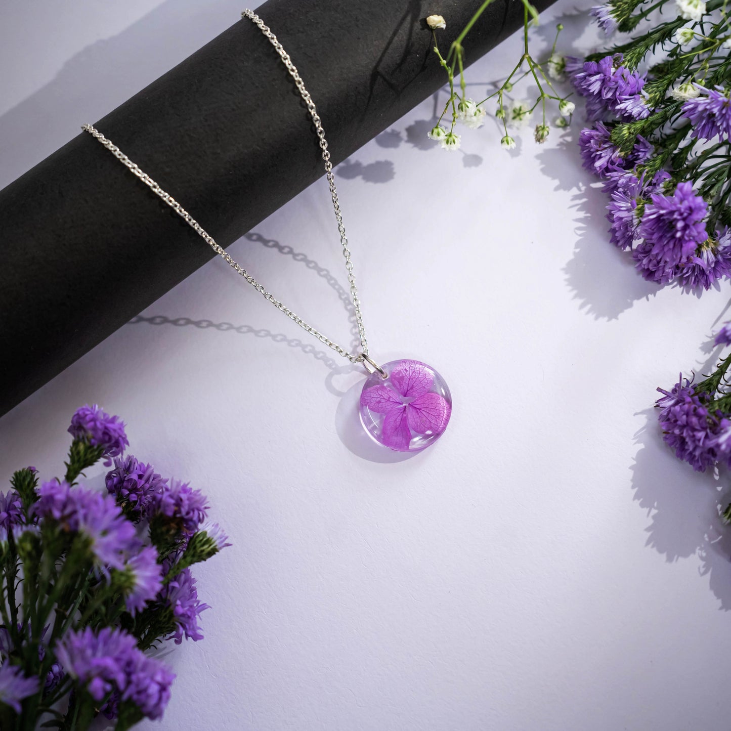 A collection of handmade resin art pendants, showcasing intricate floral designs preserved in clear resin, attached to delicate necklaces.