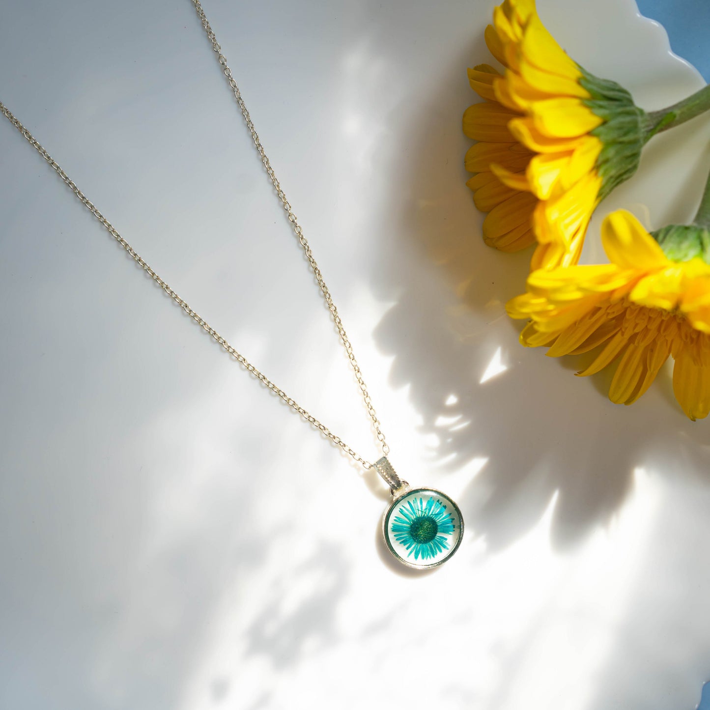A collection of handmade resin art pendants, showcasing intricate floral designs preserved in clear resin, attached to delicate necklaces.