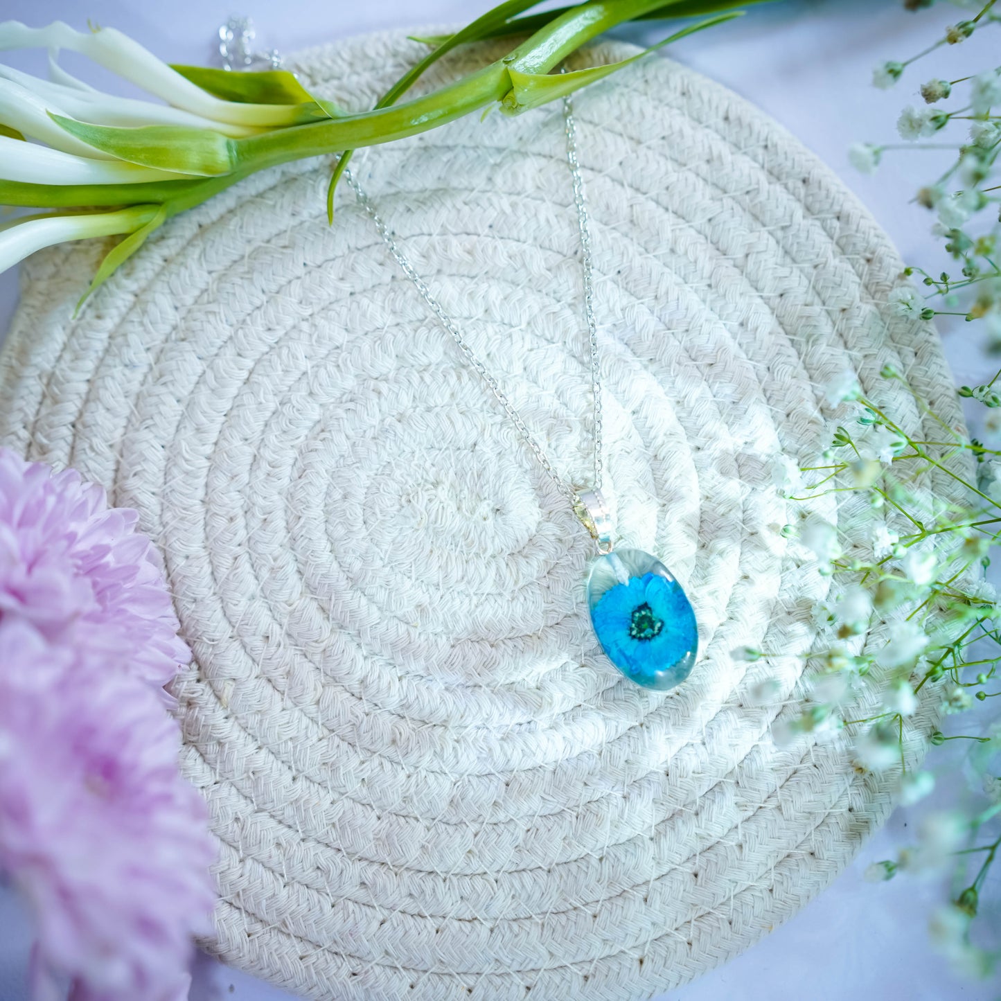 A collection of handmade resin art pendants, showcasing intricate floral designs preserved in clear resin, attached to delicate necklaces.