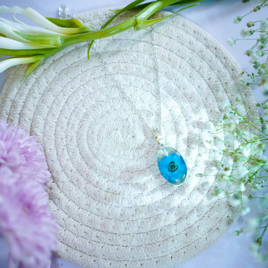 A collection of handmade resin art pendants, showcasing intricate floral designs preserved in clear resin, attached to delicate necklaces.