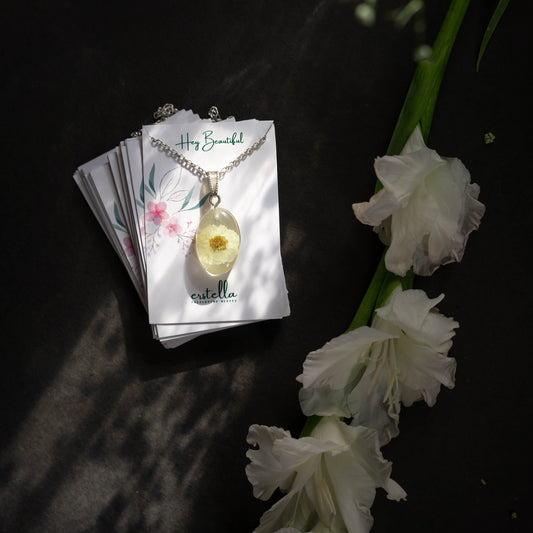 A collection of handmade resin art pendants, showcasing intricate floral designs preserved in clear resin, attached to delicate necklaces.