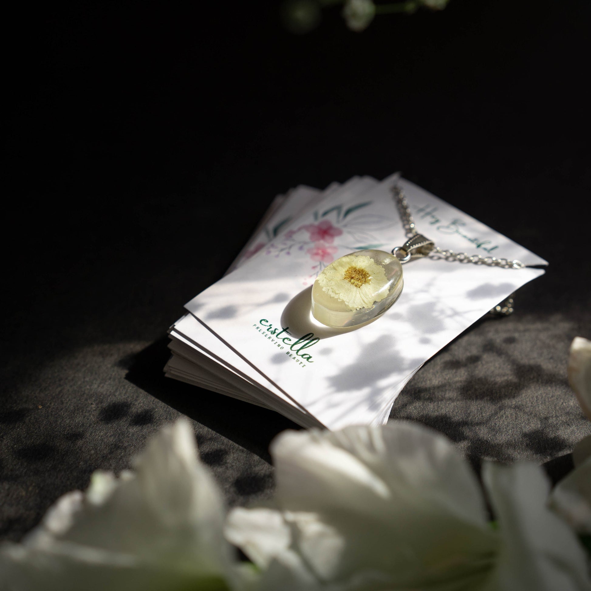 A collection of handmade resin art pendants, showcasing intricate floral designs preserved in clear resin, attached to delicate necklaces.