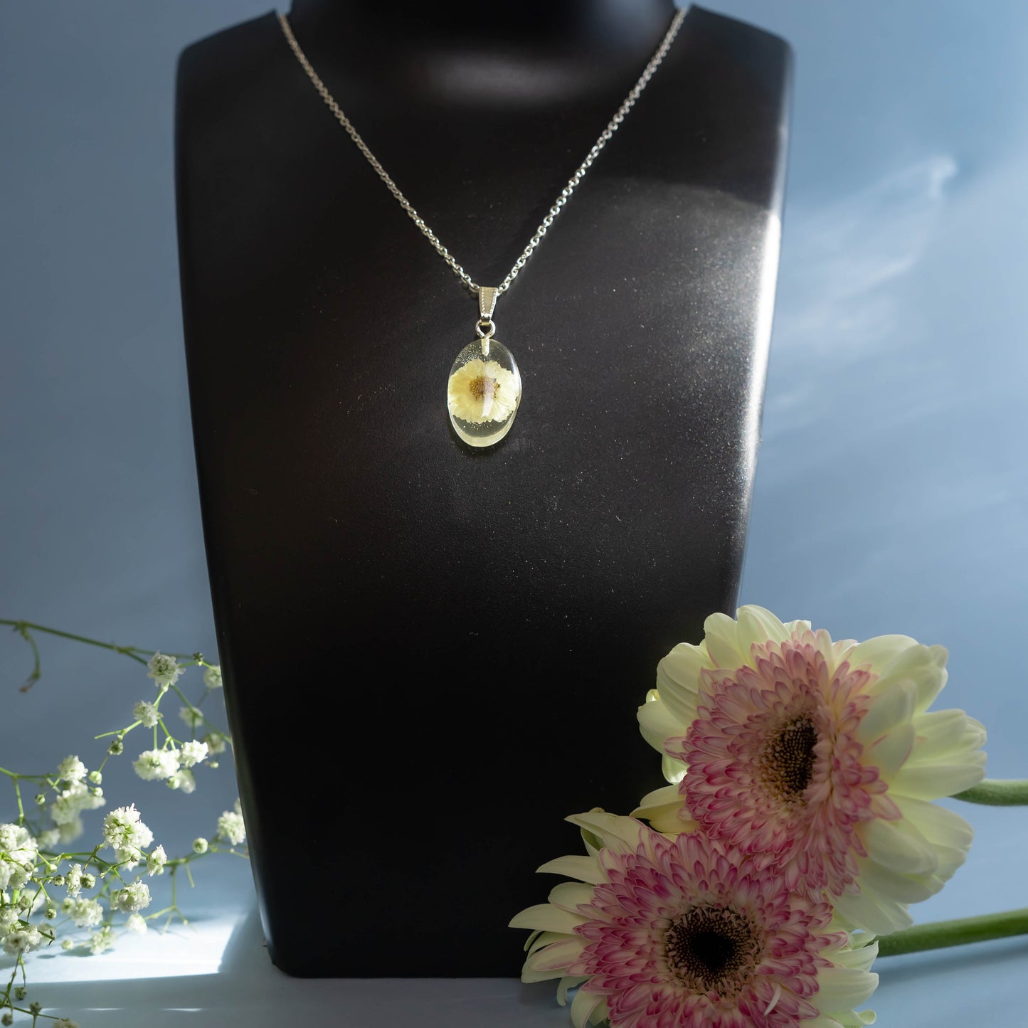 A collection of handmade resin art pendants, showcasing intricate floral designs preserved in clear resin, attached to delicate necklaces.