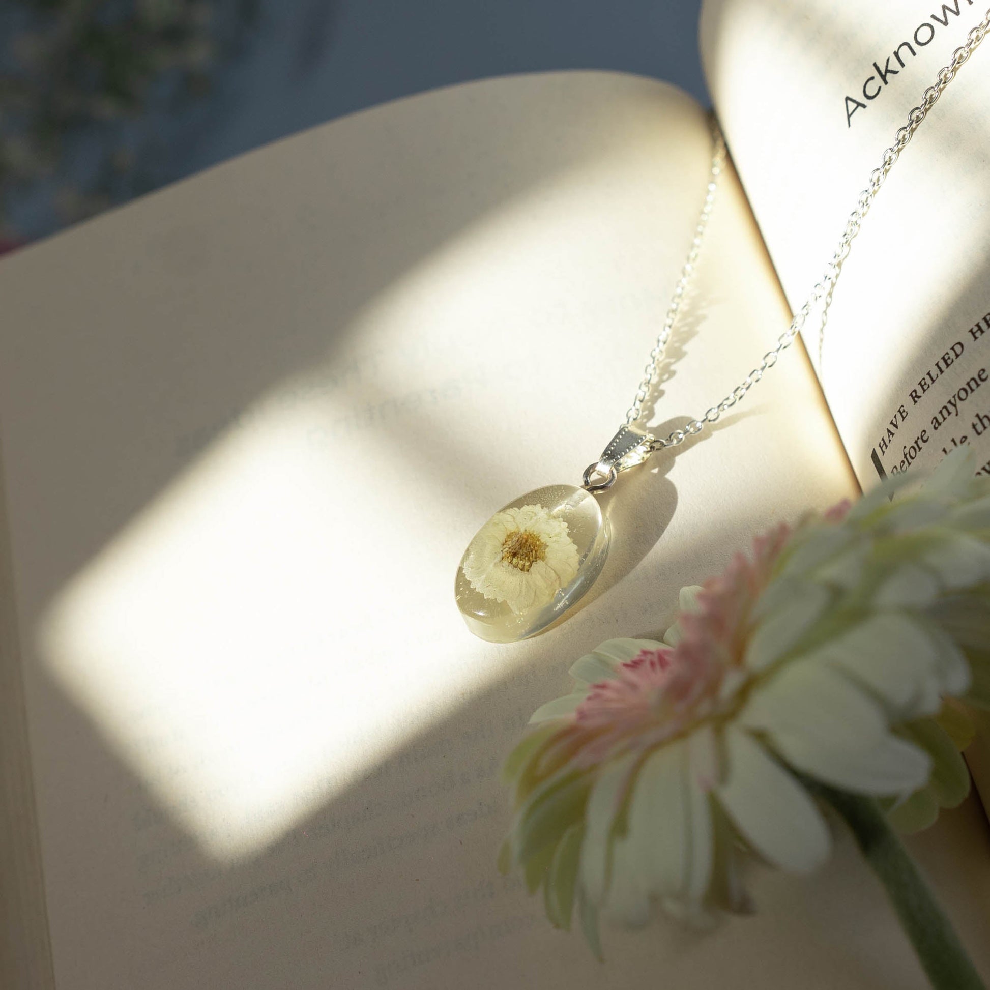 A collection of handmade resin art pendants, showcasing intricate floral designs preserved in clear resin, attached to delicate necklaces.