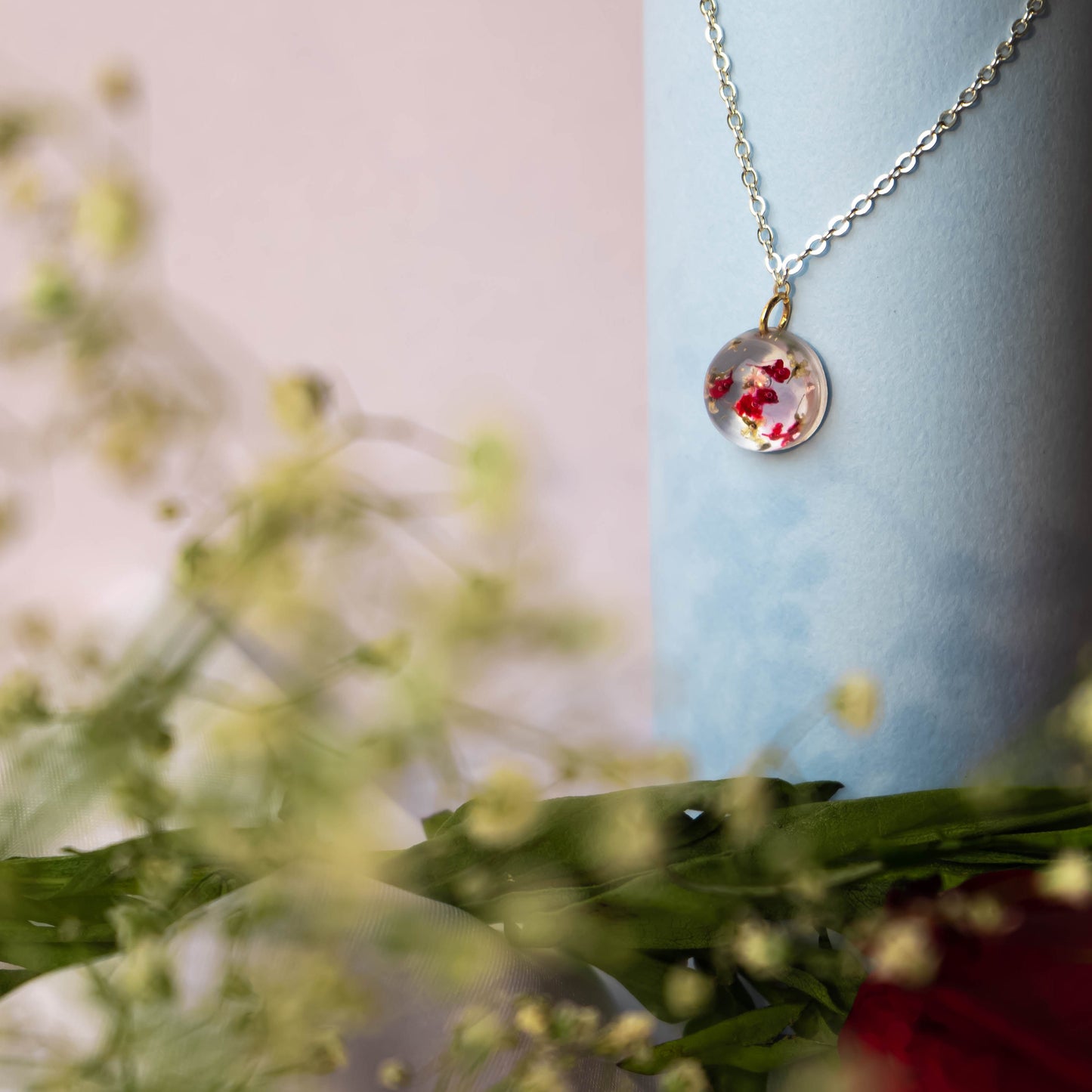 A collection of handmade resin art pendants, showcasing intricate floral designs preserved in clear resin, attached to delicate necklaces.