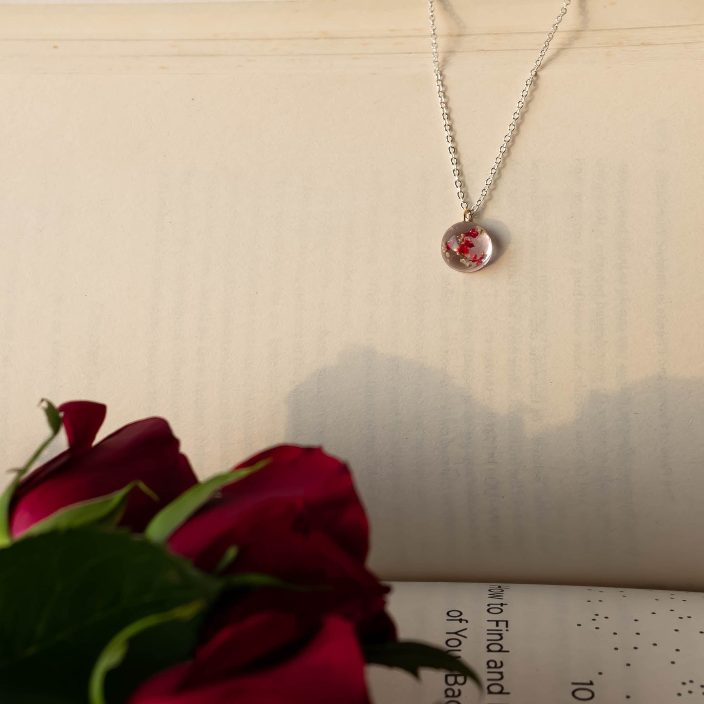 A collection of handmade resin art pendants, showcasing intricate floral designs preserved in clear resin, attached to delicate necklaces.