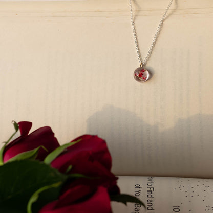 A collection of handmade resin art pendants, showcasing intricate floral designs preserved in clear resin, attached to delicate necklaces.