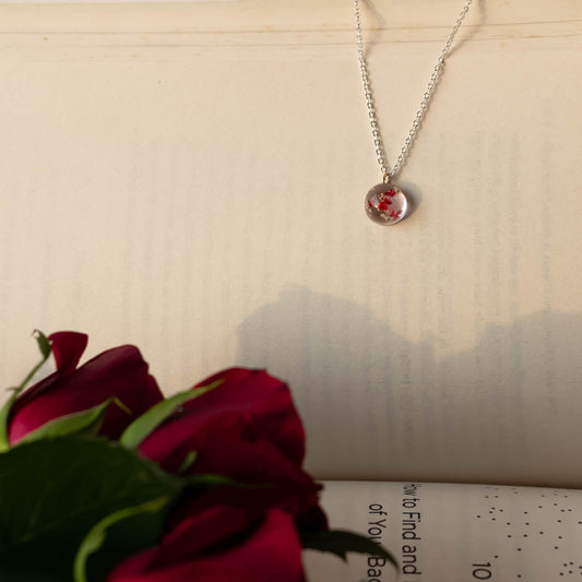 A collection of handmade resin art pendants, showcasing intricate floral designs preserved in clear resin, attached to delicate necklaces.