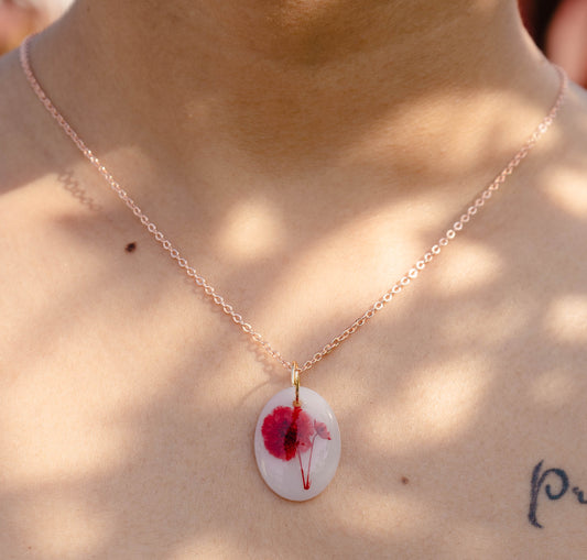 A collection of handmade resin art pendants, showcasing intricate floral designs preserved in clear resin, attached to delicate necklaces.