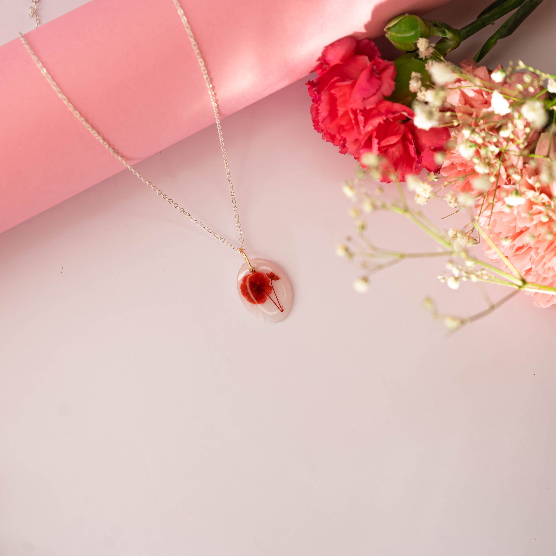 A collection of handmade resin art pendants, showcasing intricate floral designs preserved in clear resin, attached to delicate necklaces.