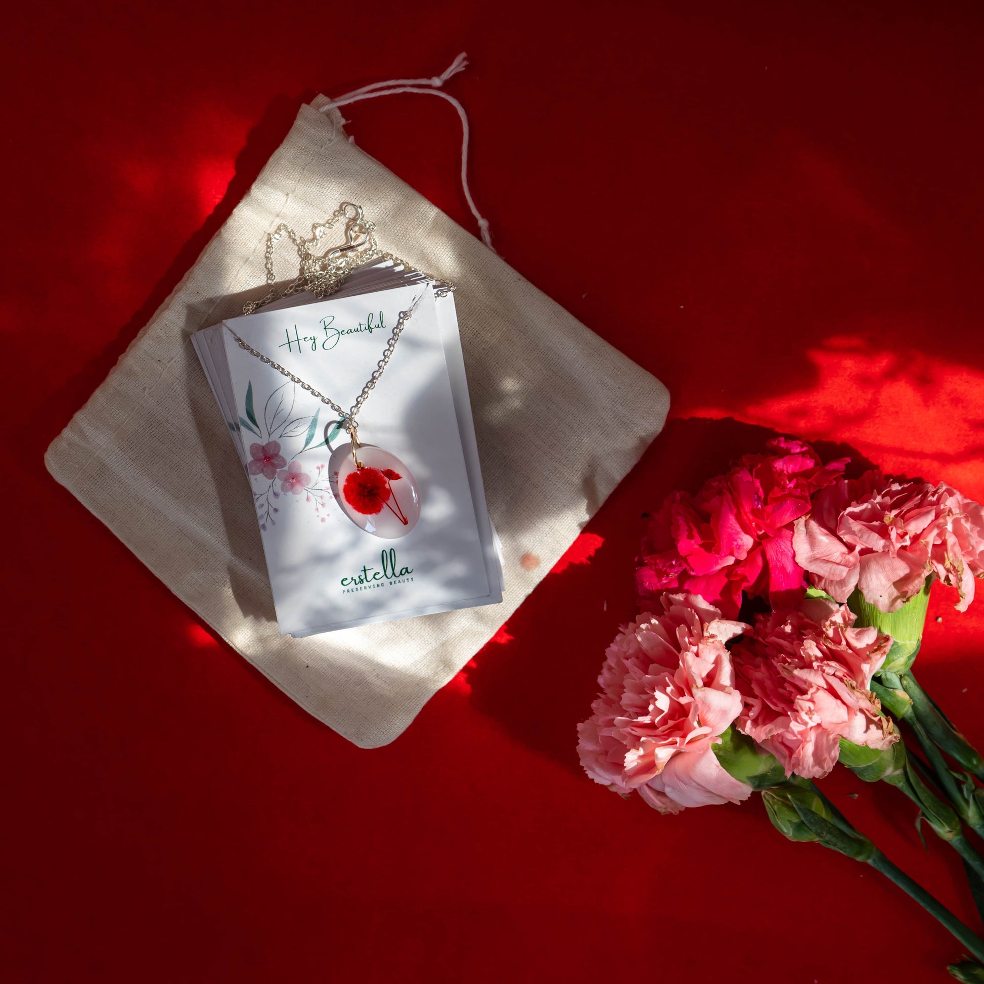 A collection of handmade resin art pendants, showcasing intricate floral designs preserved in clear resin, attached to delicate necklaces.