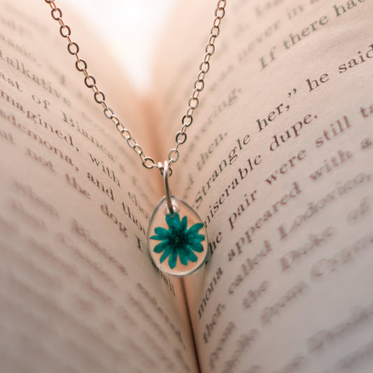 A collection of handmade resin art pendants, showcasing intricate floral designs preserved in clear resin, attached to delicate necklaces.