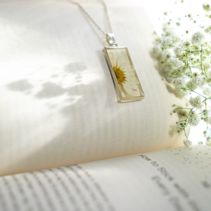 A collection of handmade resin art pendants, showcasing intricate floral designs preserved in clear resin, attached to delicate necklaces.