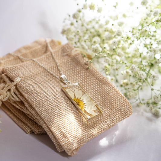 A collection of handmade resin art pendants, showcasing intricate floral designs preserved in clear resin, attached to delicate necklaces.