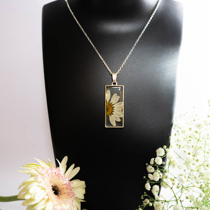 A collection of handmade resin art pendants, showcasing intricate floral designs preserved in clear resin, attached to delicate necklaces.