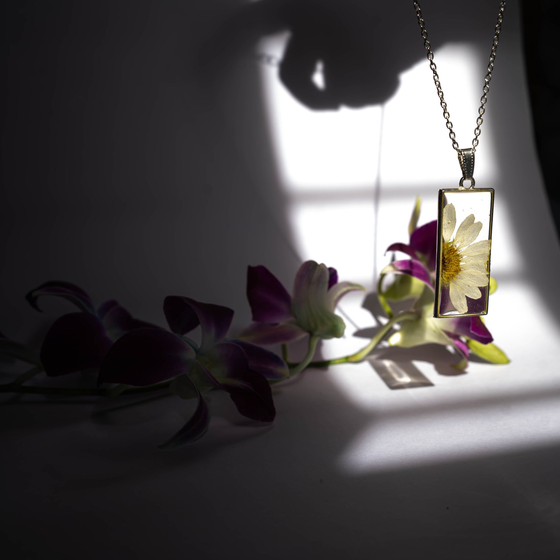 A collection of handmade resin art pendants, showcasing intricate floral designs preserved in clear resin, attached to delicate necklaces.