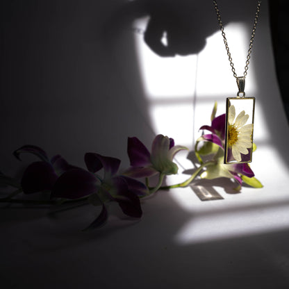 A collection of handmade resin art pendants, showcasing intricate floral designs preserved in clear resin, attached to delicate necklaces.
