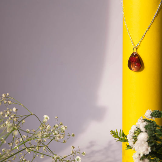 A collection of handmade resin art pendants, showcasing intricate floral designs preserved in clear resin, attached to delicate necklaces.