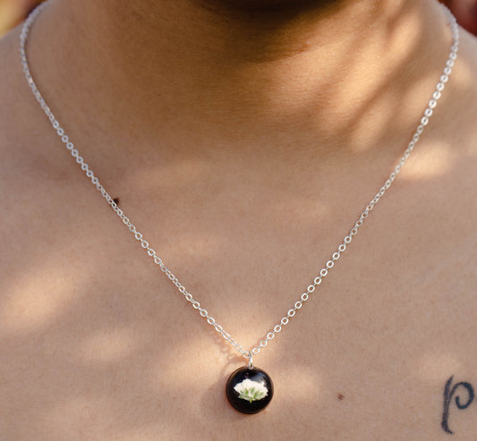 A collection of handmade resin art pendants, showcasing intricate floral designs preserved in clear resin, attached to delicate necklaces.