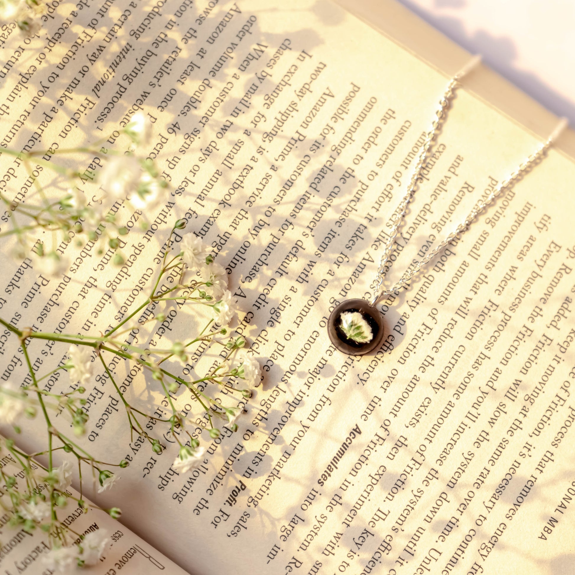 A collection of handmade resin art pendants, showcasing intricate floral designs preserved in clear resin, attached to delicate necklaces.