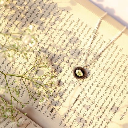 A collection of handmade resin art pendants, showcasing intricate floral designs preserved in clear resin, attached to delicate necklaces.