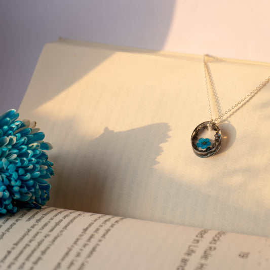 A collection of handmade resin art pendants, showcasing intricate floral designs preserved in clear resin, attached to delicate necklaces.