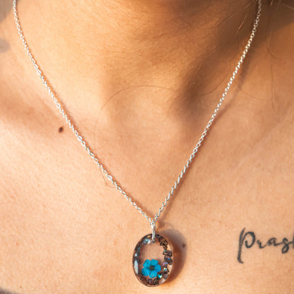 A collection of handmade resin art pendants, showcasing intricate floral designs preserved in clear resin, attached to delicate necklaces.