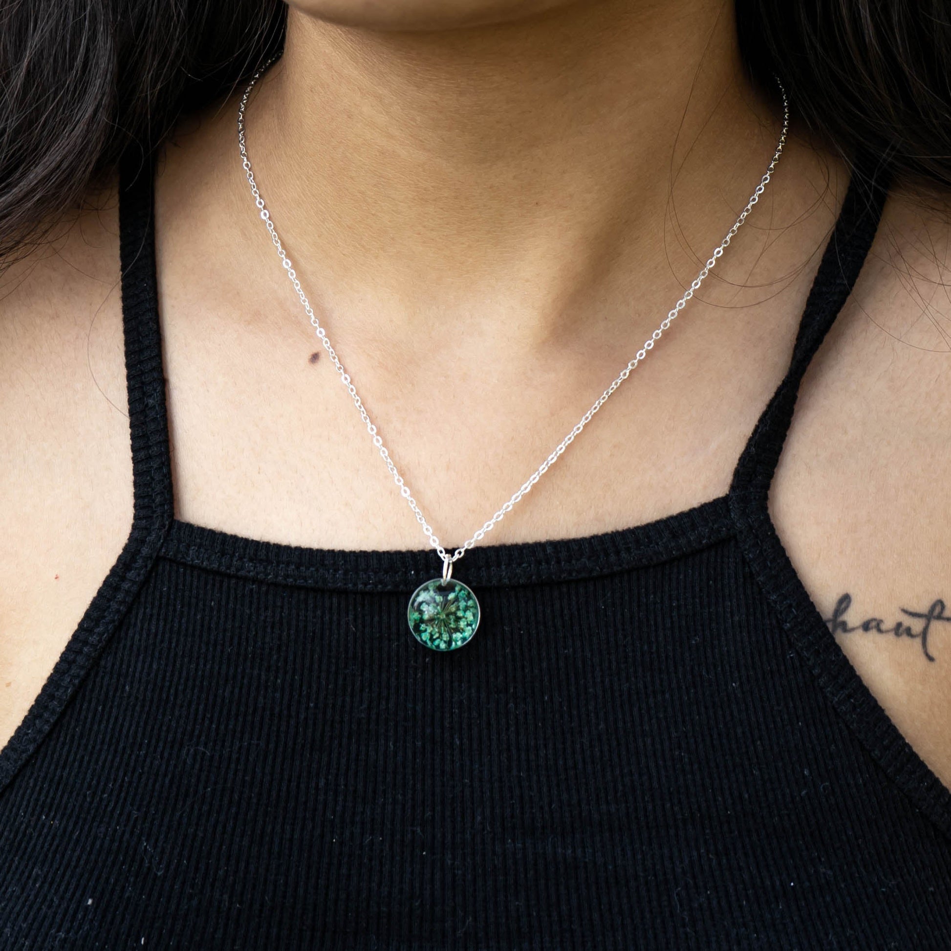 A collection of handmade resin art pendants, showcasing intricate floral designs preserved in clear resin, attached to delicate necklaces.