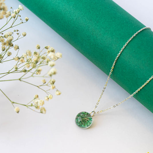 A collection of handmade resin art pendants, showcasing intricate floral designs preserved in clear resin, attached to delicate necklaces.