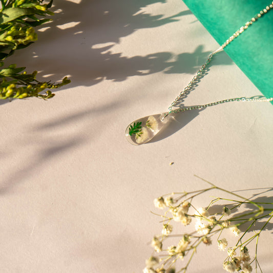 A collection of handmade resin art pendants, showcasing intricate floral designs preserved in clear resin, attached to delicate necklaces.