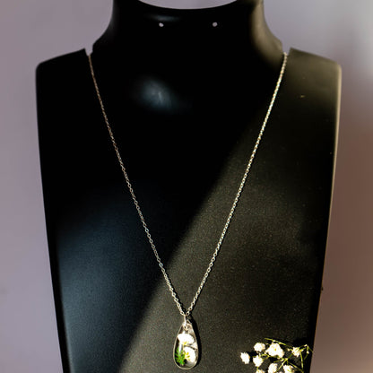 A collection of handmade resin art pendants, showcasing intricate floral designs preserved in clear resin, attached to delicate necklaces.