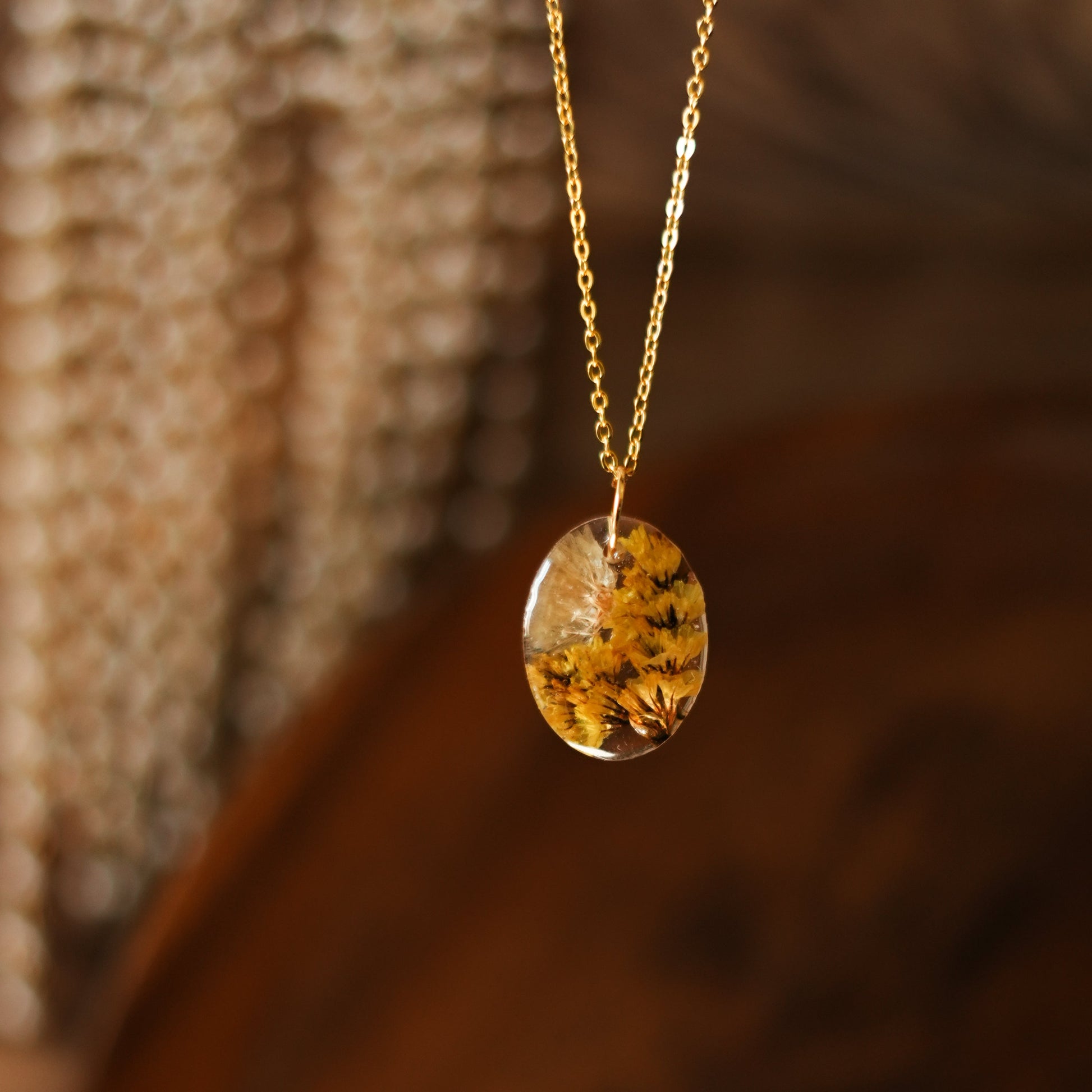 A collection of handmade resin art pendants, showcasing intricate floral designs preserved in clear resin, attached to delicate necklaces.