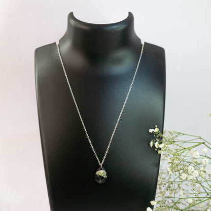 A collection of handmade resin art pendants, showcasing intricate floral designs preserved in clear resin, attached to delicate necklaces.