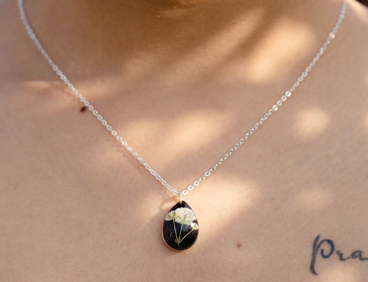 A collection of handmade resin art pendants, showcasing intricate floral designs preserved in clear resin, attached to delicate necklaces.