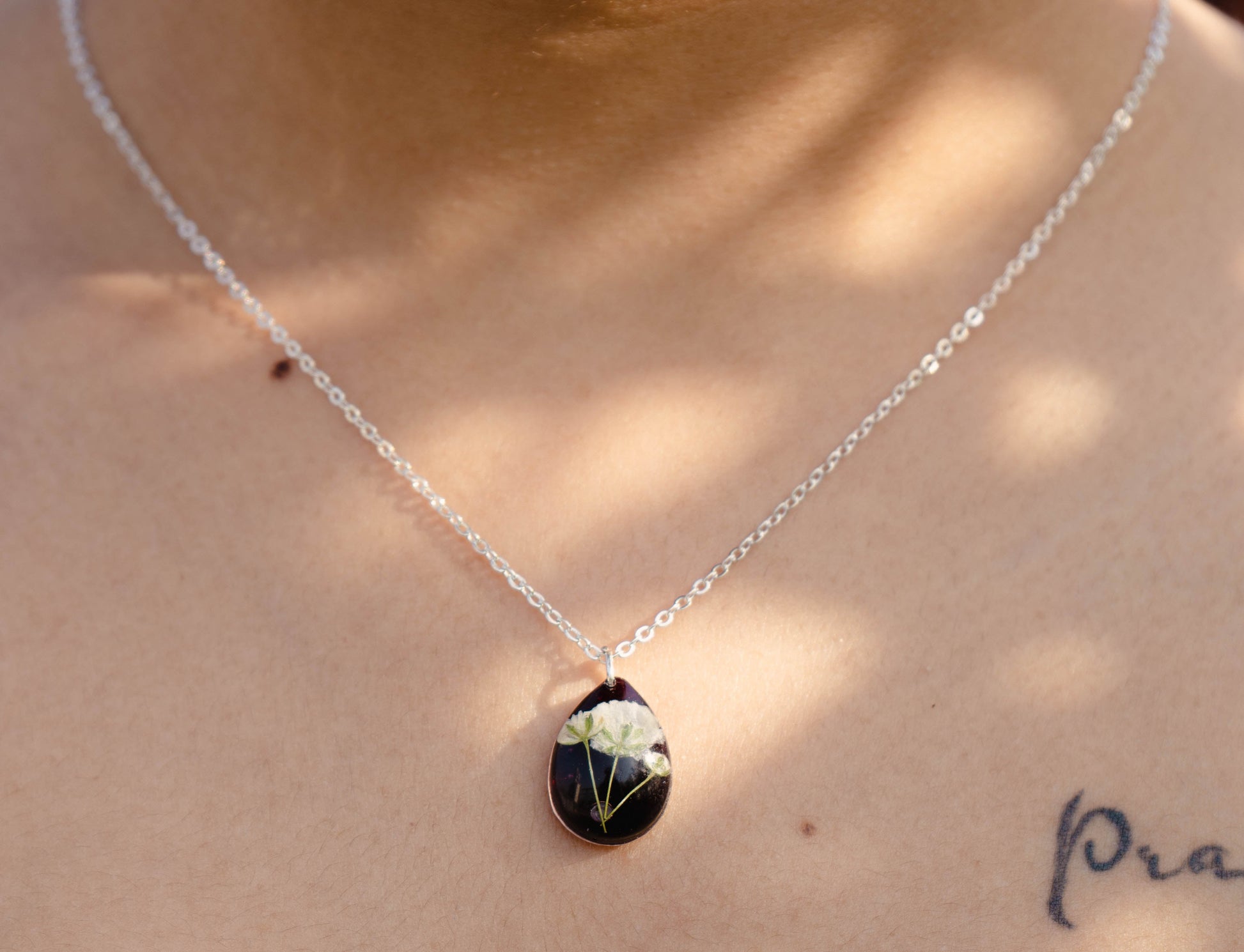 A collection of handmade resin art pendants, showcasing intricate floral designs preserved in clear resin, attached to delicate necklaces.