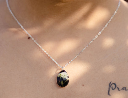 A collection of handmade resin art pendants, showcasing intricate floral designs preserved in clear resin, attached to delicate necklaces.