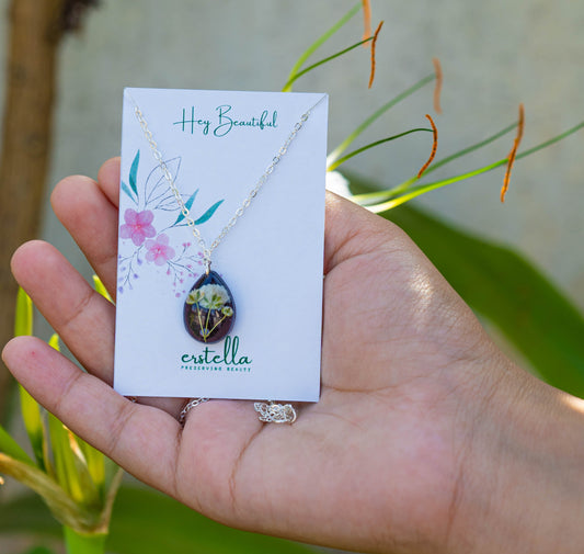A collection of handmade resin art pendants, showcasing intricate floral designs preserved in clear resin, attached to delicate necklaces.