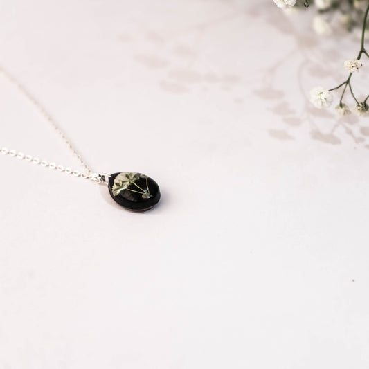 A collection of handmade resin art pendants, showcasing intricate floral designs preserved in clear resin, attached to delicate necklaces.