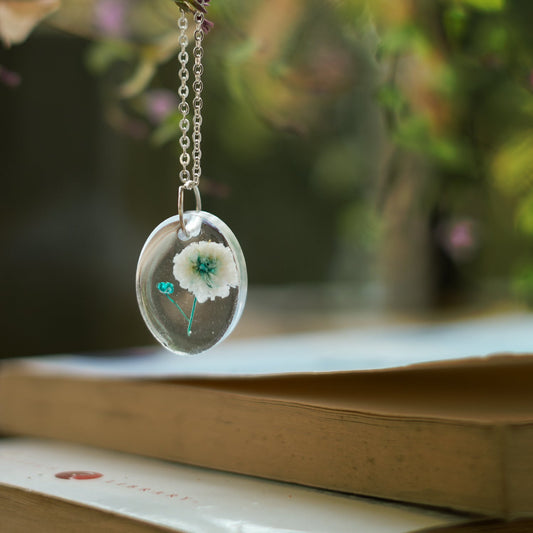 A collection of handmade resin art pendants, showcasing intricate floral designs preserved in clear resin, attached to delicate necklaces.