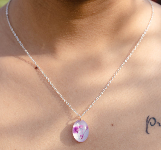 A collection of handmade resin art pendants, showcasing intricate floral designs preserved in clear resin, attached to delicate necklaces.